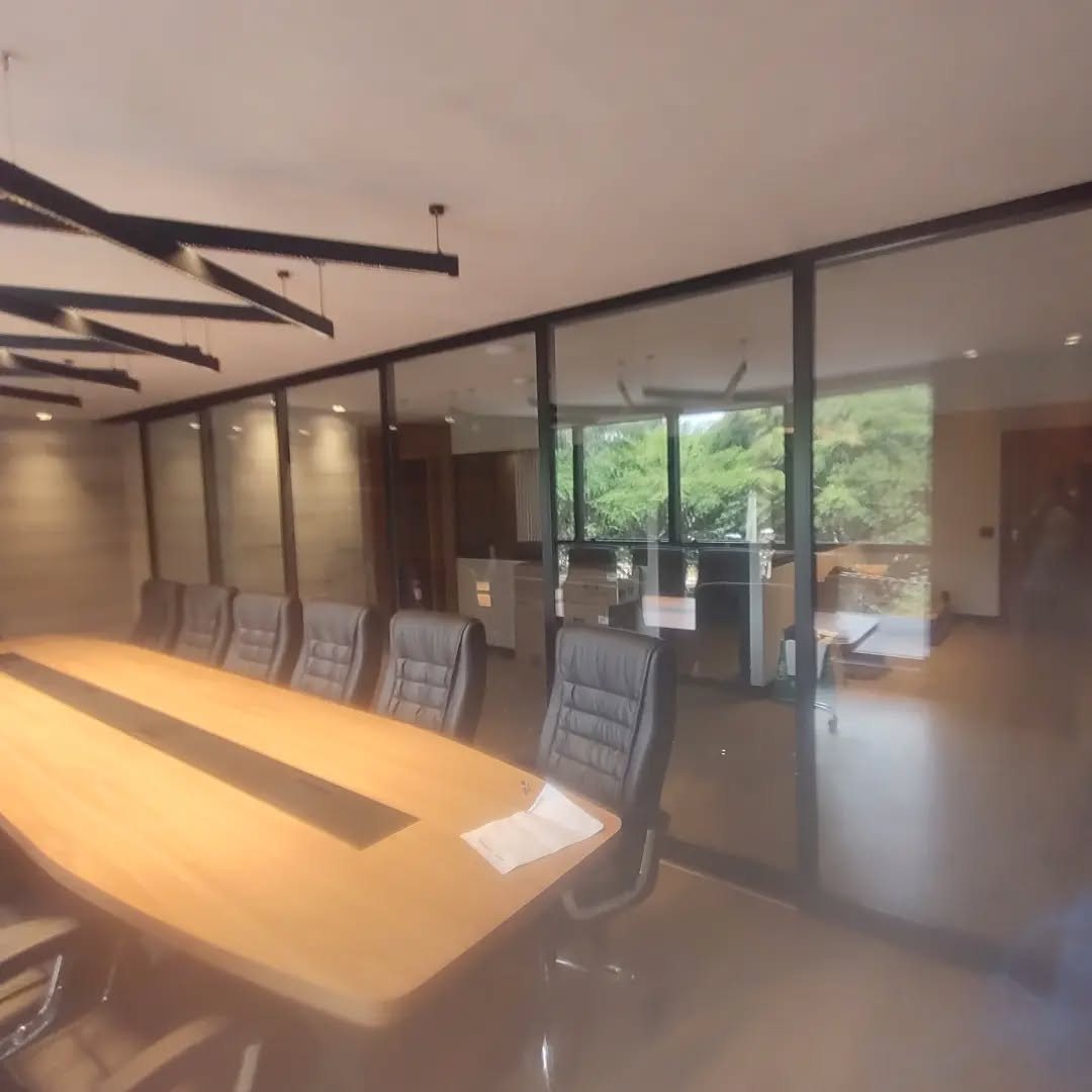 Divisória de vidro com esquadrias de alumínio preto em sala corporativa